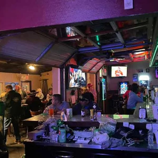 Patrons enjoying drinks and watching sports on multiple screens at Wolfies Sports Bar.