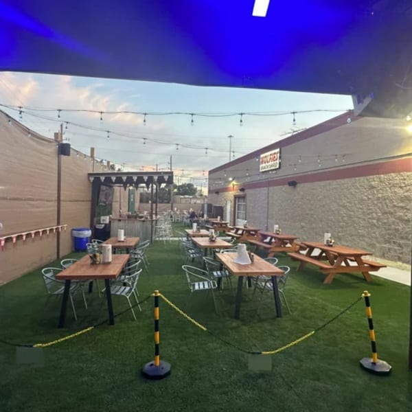 Wolfies Restaurant and Sports Bar's outdoor patio with picnic tables, string lights, and artificial turf.