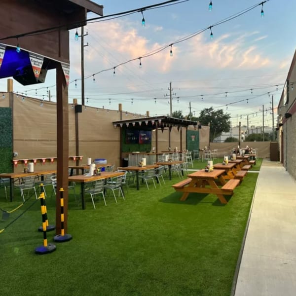 Outdoor patio at Wolfies Sports Bar with picnic tables, string lights, and a bar area.