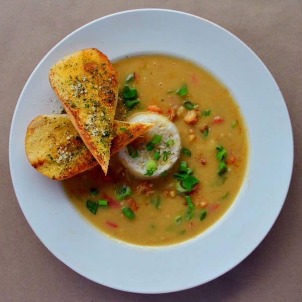 A bowl of Wolfies' creamy crawfish etouffee with rice, green onions, and garlic bread.
