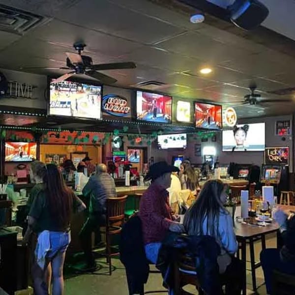 Wolfies sports bar interior with multiple TVs showing sports and people seated at the bar and tables.
