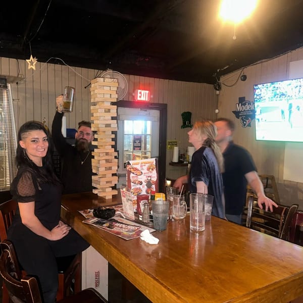 Patrons playing a giant Jenga game at the bar in Wolfies Restaurant and Sports Bar.