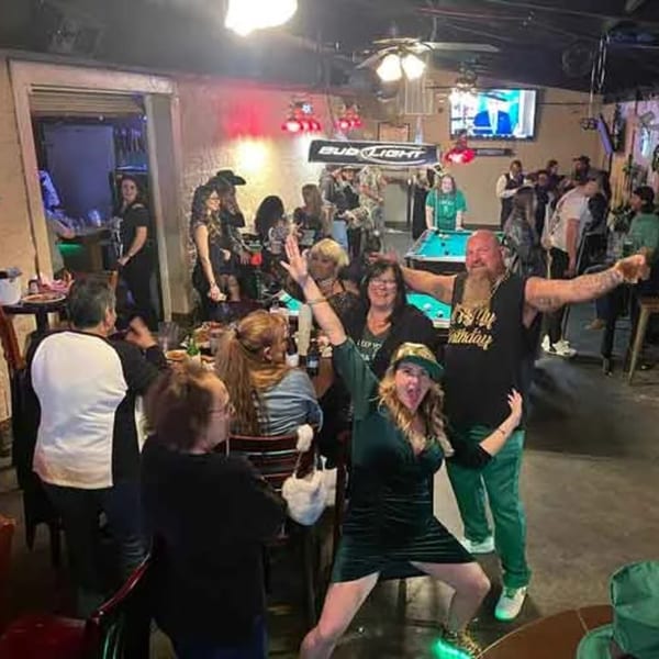 Patrons enjoying a lively night at Wolfies Sports Bar, with a pool table and Bud Light banner visible.