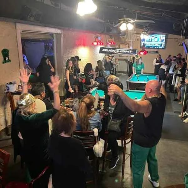 Patrons enjoying a lively evening at Wolfies Sports Bar, with people playing pool and socializing.