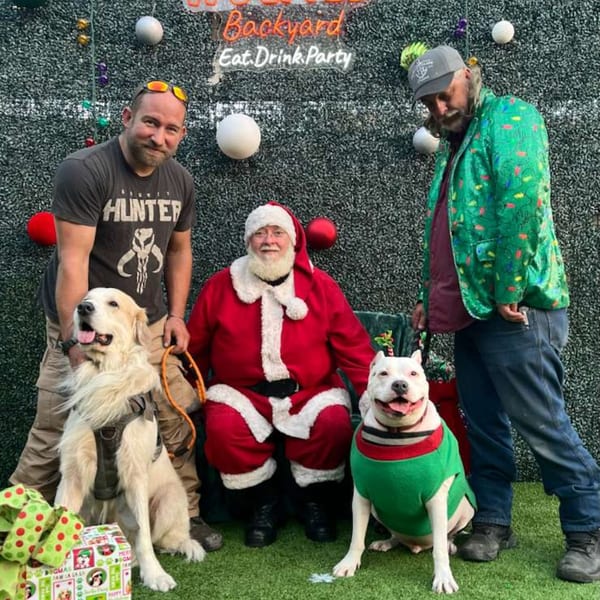 Santa, two men, and two dogs pose for a festive photo at Wolfies Restaurant and Sports Bar.