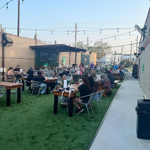 Wolfies Restaurant and Sports Bar's outdoor patio with people dining at tables on artificial turf.