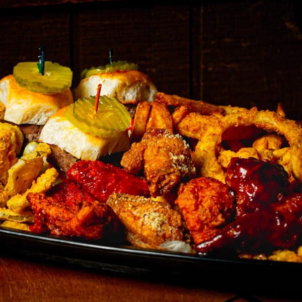 A platter of Wolfies' sliders, onion rings, fried pickles, and various chicken wings.