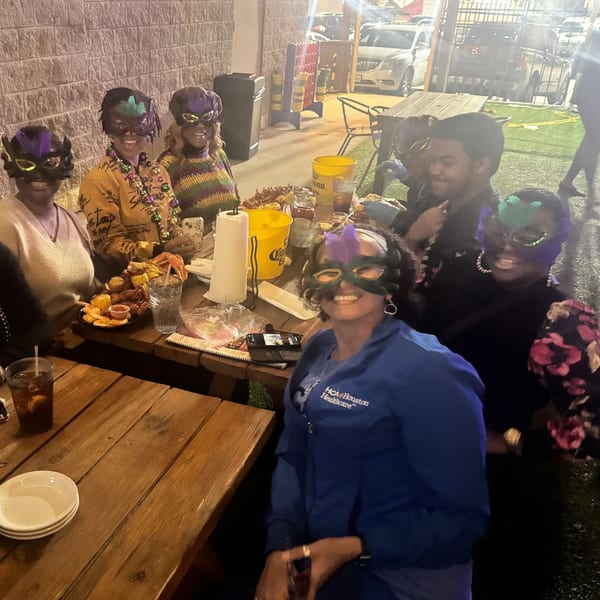 People wearing Mardi Gras masks and beads enjoy food and drinks at Wolfies Restaurant and Sports Bar.