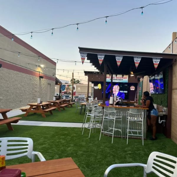 Wolfies sports bar outdoor patio with picnic tables, a bar, and string lights under a clear sky.