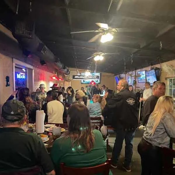 Patrons socialize and dine in the dimly lit, bustling interior of Wolfies Restaurant and Sports Bar.