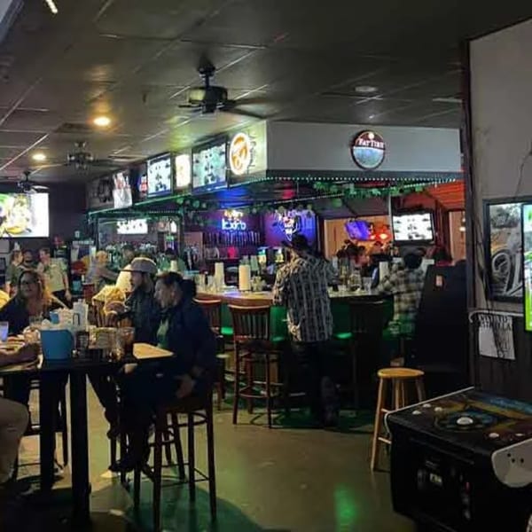 Patrons enjoying drinks and conversation at the bar and high-top tables in Wolfies Sports Bar.